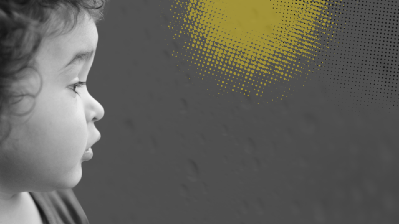 Black-and-white photo of a toddler in profile looking out a rain-covered window with yellow and black dots representing pollution.