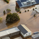 Aerial view of neighborhood in Lismore, Australia submerged in muddy floodwater. Rooftops and trees are visible