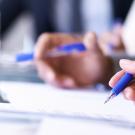 hands holding pencils on paper during meeting
